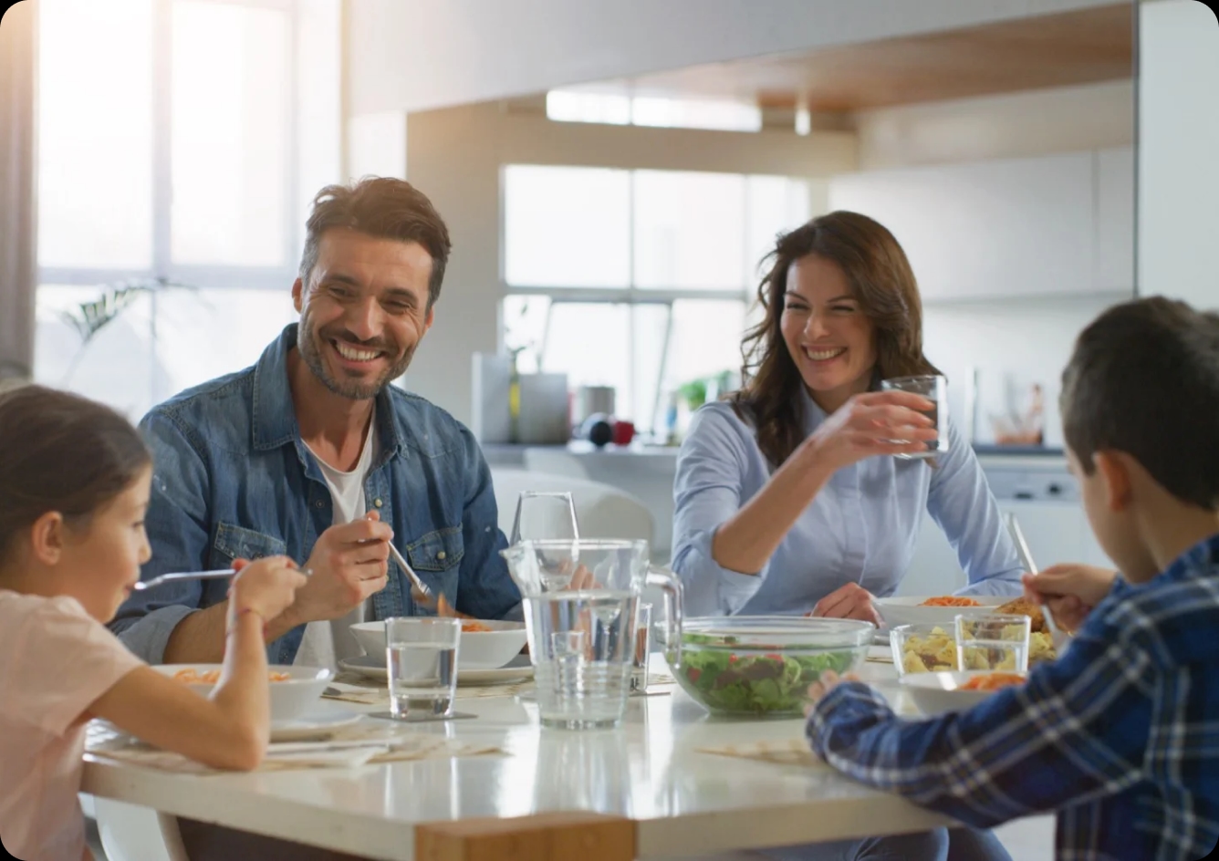 Uma familia comendo sorridente na mesa de jantar